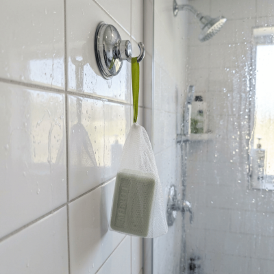 Sac filet moussant contenant un savon solide suspendu dans une douche